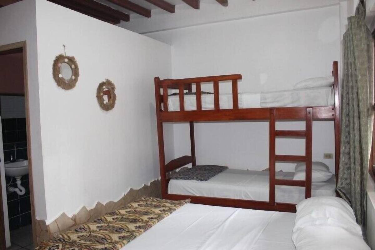 A room with bunk beds, a patterned bedspread, and two wall-mounted wreaths.