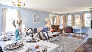 A dining area with a table set for a meal, a sofa, and a chair in the background. - Sleeps 8, Minutes to Nauset Beach! (Orleans)
