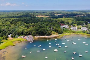 A coastal area with a marina filled with boats, surrounded by dense greenery and residential buildings.