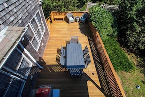 A deck with a table and chairs, surrounded by a wooden fence and greenery.