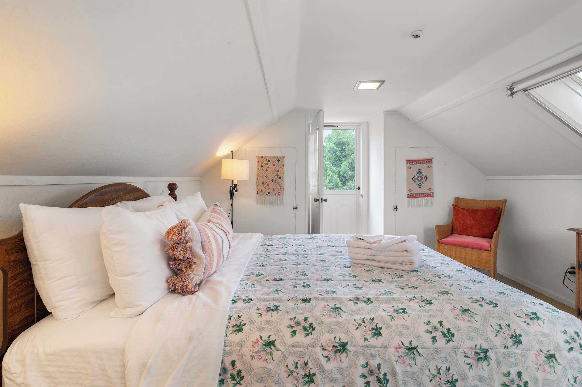A bedroom with a bed, a chair, a lamp, and a door leading outside.
