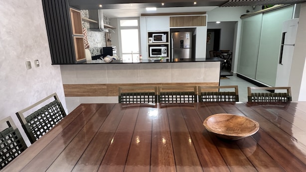 A modern kitchen with a central island, built-in appliances, and a dining area with a wooden table and chairs.