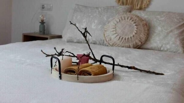 A neatly made bed with a white bedspread, a decorative wall hanging, and a bedside table with a lamp. - Apartamento El Picu (Collanzo)