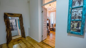 Ein Flur mit Holzboden, einem rustikalen Spiegel und einer Tür zu einem Raum mit einem blau gerahmten Bild.