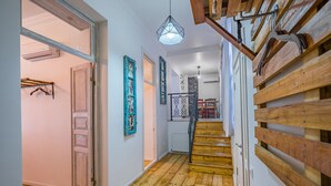 Eine Holztreppe führt zu einer zweiten Etage, darüber hängt eine Leuchte.
