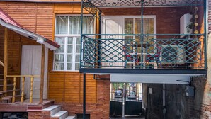 Ein Holzgebäude mit Balkon, Treppe und Tor zu einem Parkplatz.