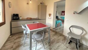 Cocina compacta con comedor, refrigerador, cafetera y un reloj en la pared.
