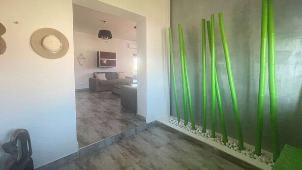 Un interior moderno con diseño minimalista, que presenta una pared gris con detalles verticales verdes, un sofá gris y una pequeña mesa.