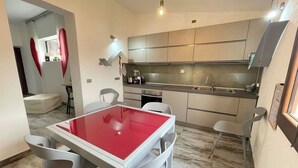 Cocina moderna con comedor, que incluye una mesa roja y sillas blancas.