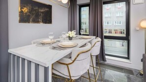 Un comedor moderno con una mesa de mármol, sillas blancas y una lámpara colgante.