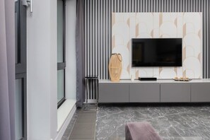 A modern living room with a large flat-screen TV mounted on a wall with a geometric pattern.