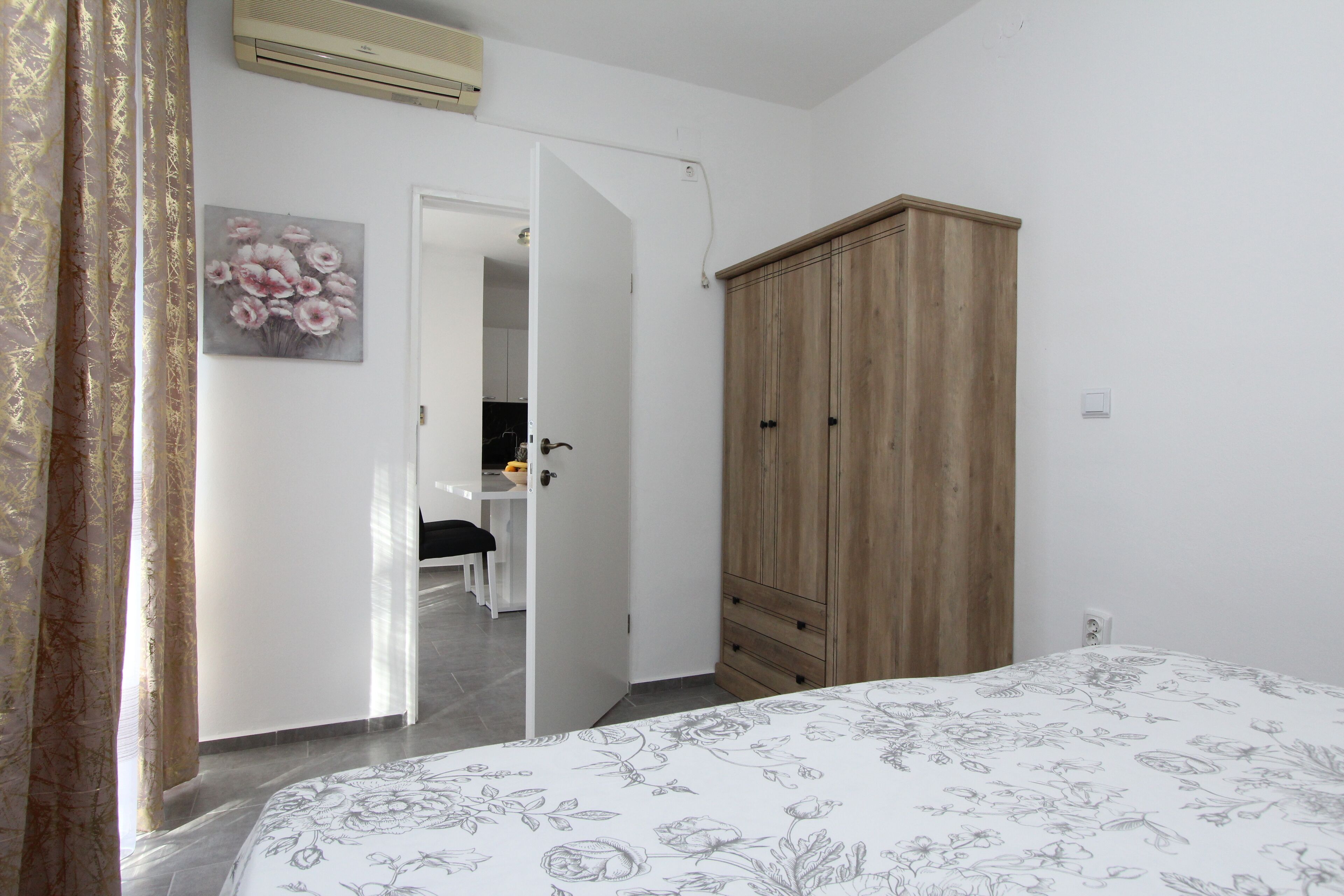A bedroom with a bed, a wardrobe, a door leading to a bathroom, and a painting on the wall.