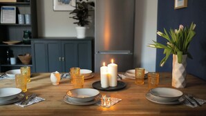 A dining table set with plates, cutlery, and candles, with a vase of flowers and a potted plant in the background. - Huge apartment with Sauna and free parking (Duisburg)