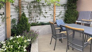 A covered patio area with a wooden pergola, a table and chairs, and a grill. - Huge apartment with Sauna and free parking (Duisburg)