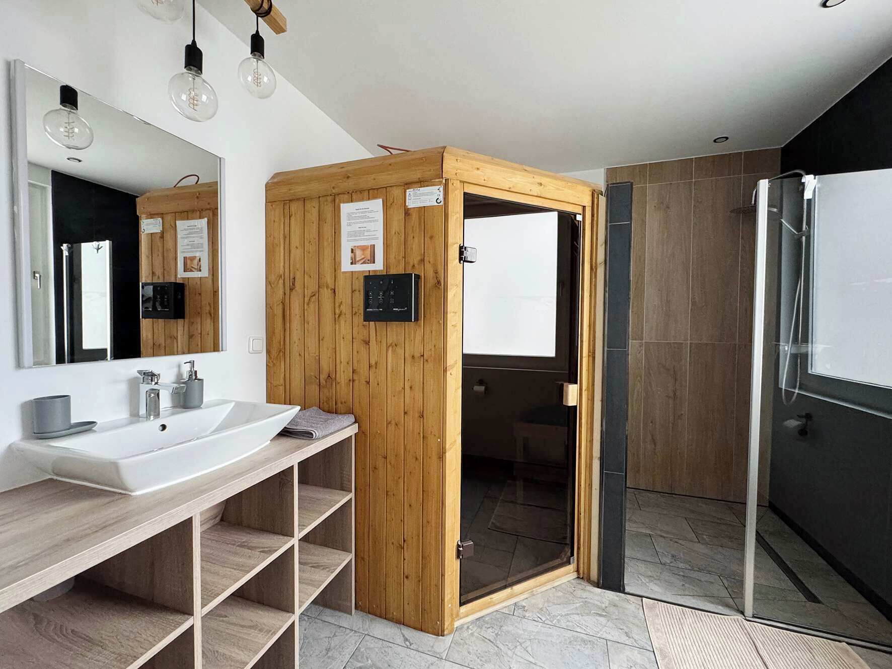 Une salle de bain moderne avec un meuble-lavabo en bois, un grand miroir et une cabine de douche en verre.
