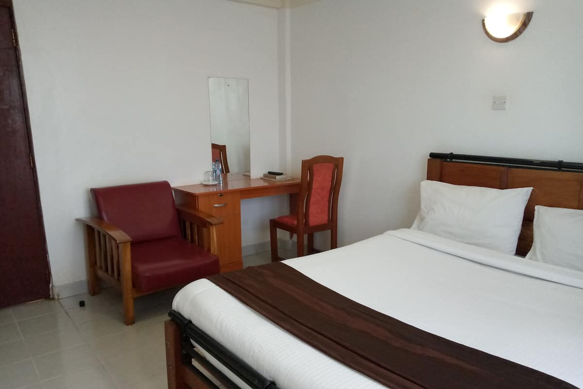A hotel room with a bed, a desk, and two chairs.