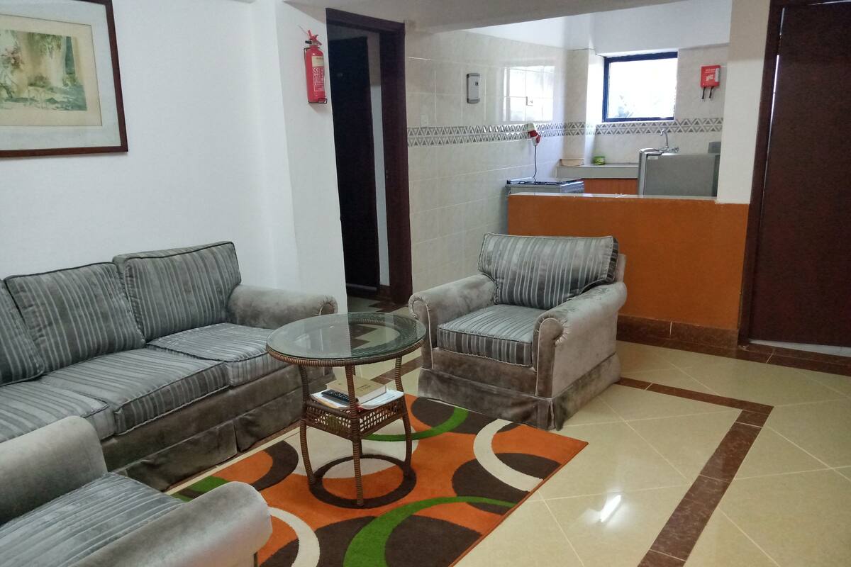 A living area with a sofa, armchair, and a glass-top coffee table.