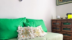 A green sofa with floral pillows, a wooden dresser with drawers, and a painting on the wall. - 2 bedroom apartment in florence (Firenze)