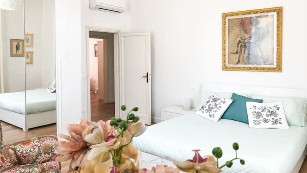 A bedroom with a bed, a nightstand, a mirror, and a door leading to another room. - 2 bedroom apartment in florence (Firenze)