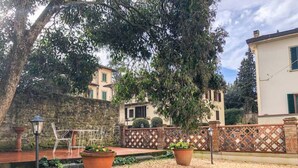 A courtyard with a stone wall, a wooden fence, and terracotta planters. - 1 bedroom apartment in florence (Firenze)