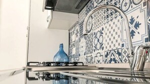A kitchen with a gas stove, a blue vase, and decorative tiles. - 1 bedroom apartment in florence (Firenze)