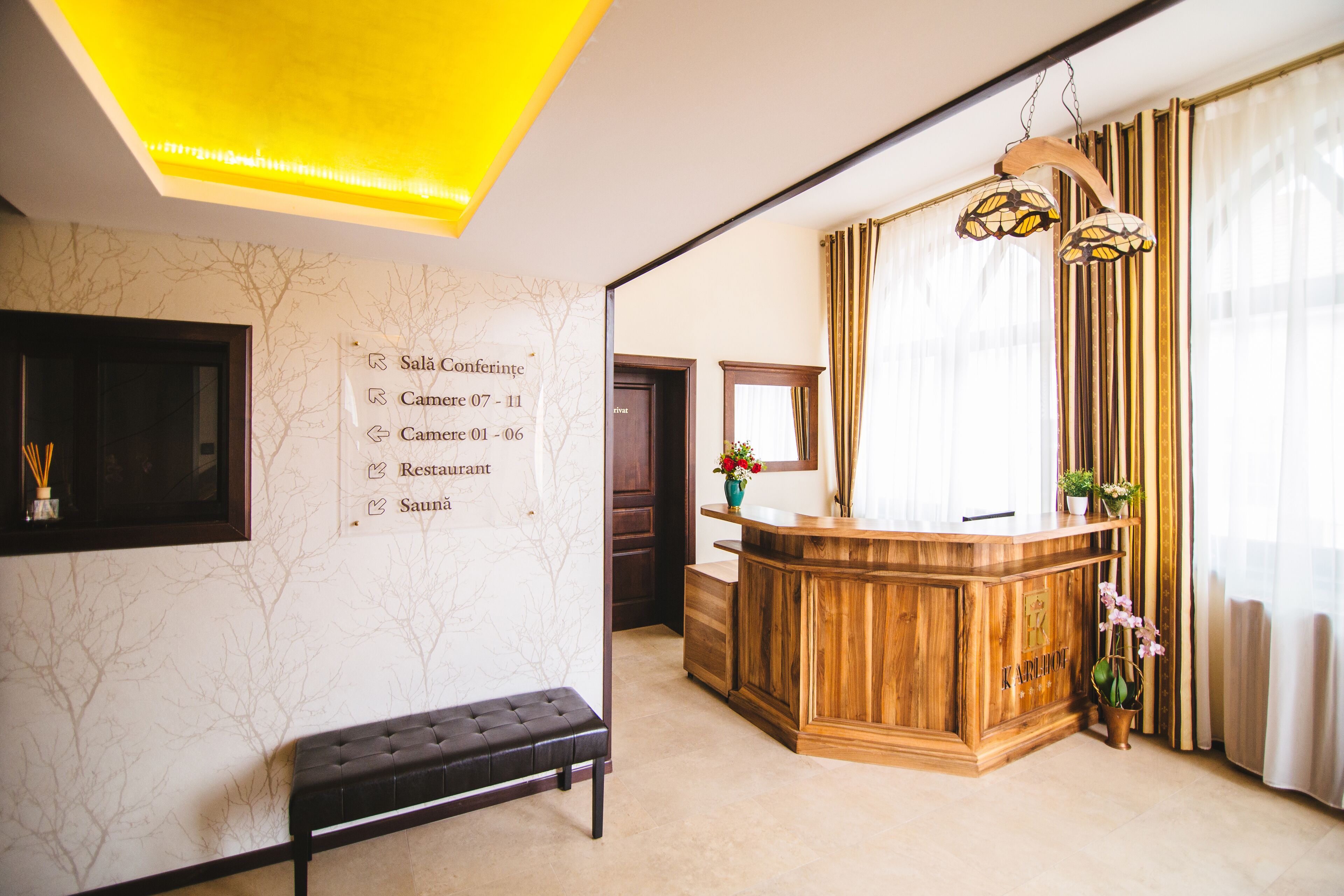 Una zona de recepción con un mostrador de madera, un banco y una pared con indicaciones.