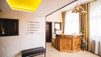 Una zona de recepción con un mostrador de madera, un banco y una pared con indicaciones.