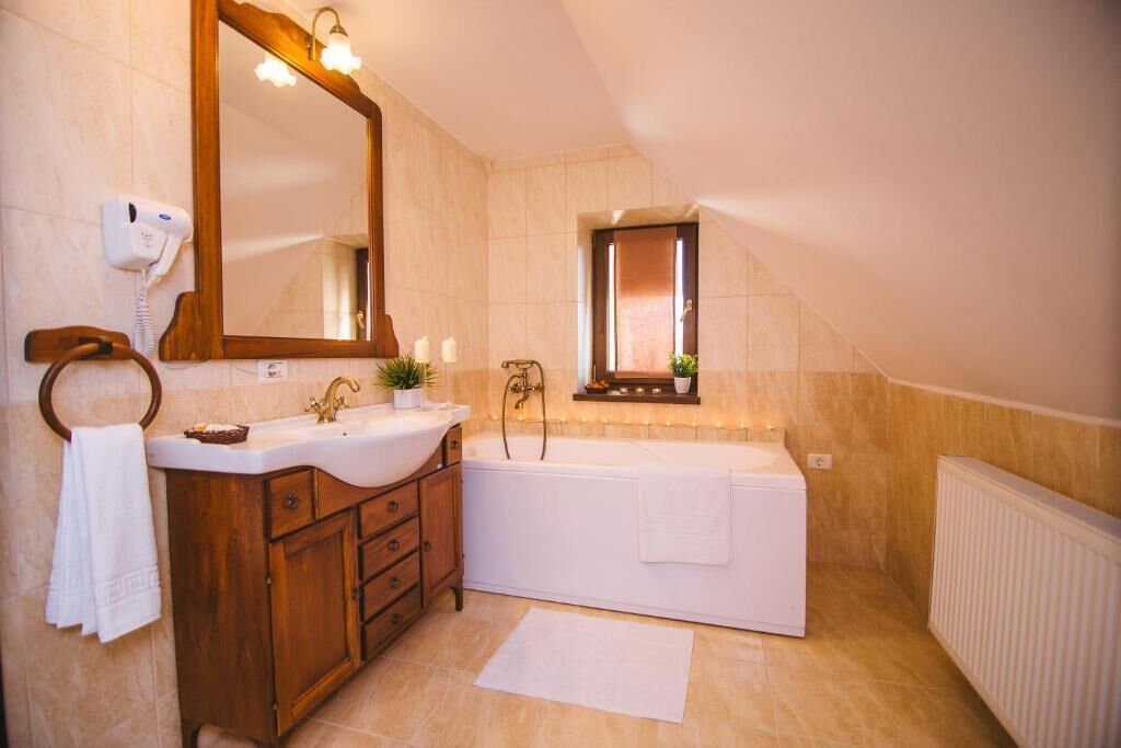 A bathroom with a wooden vanity, a large mirror, a bathtub, and a towel rack.