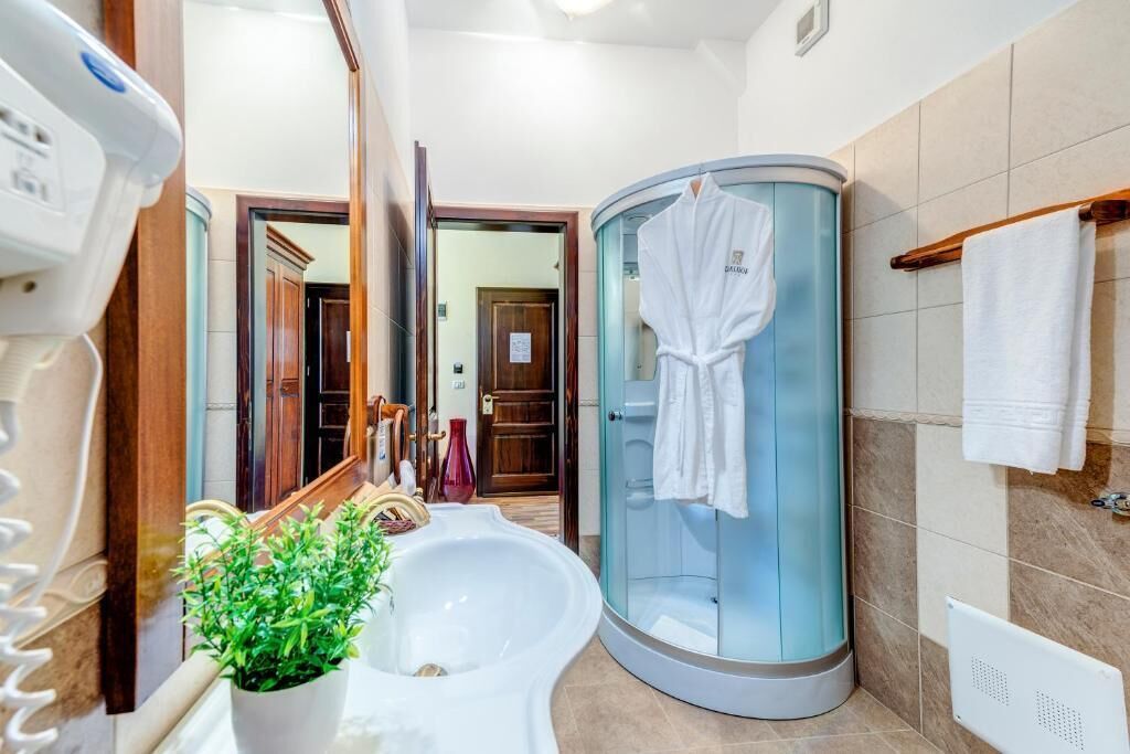 A modern bathroom with a large mirror, a sink, a glass shower enclosure, and a towel rack.