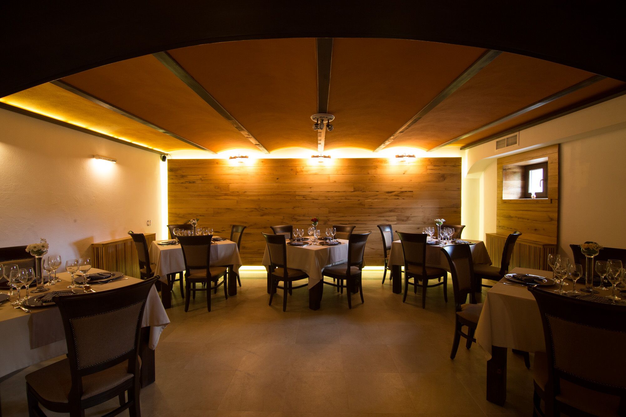 A restaurant with multiple tables, wooden walls, and warm lighting.