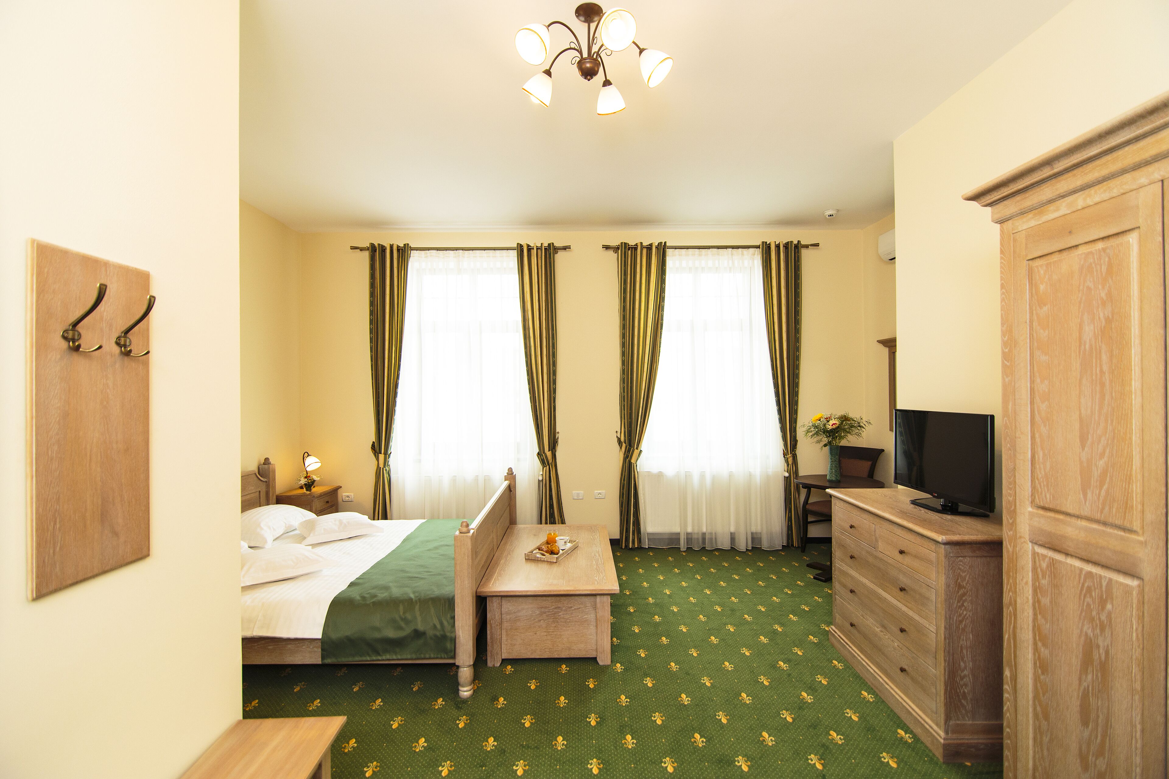 Une chambre d’hôtel avec un lit, un bureau, une commode, une télévision et des rideaux.