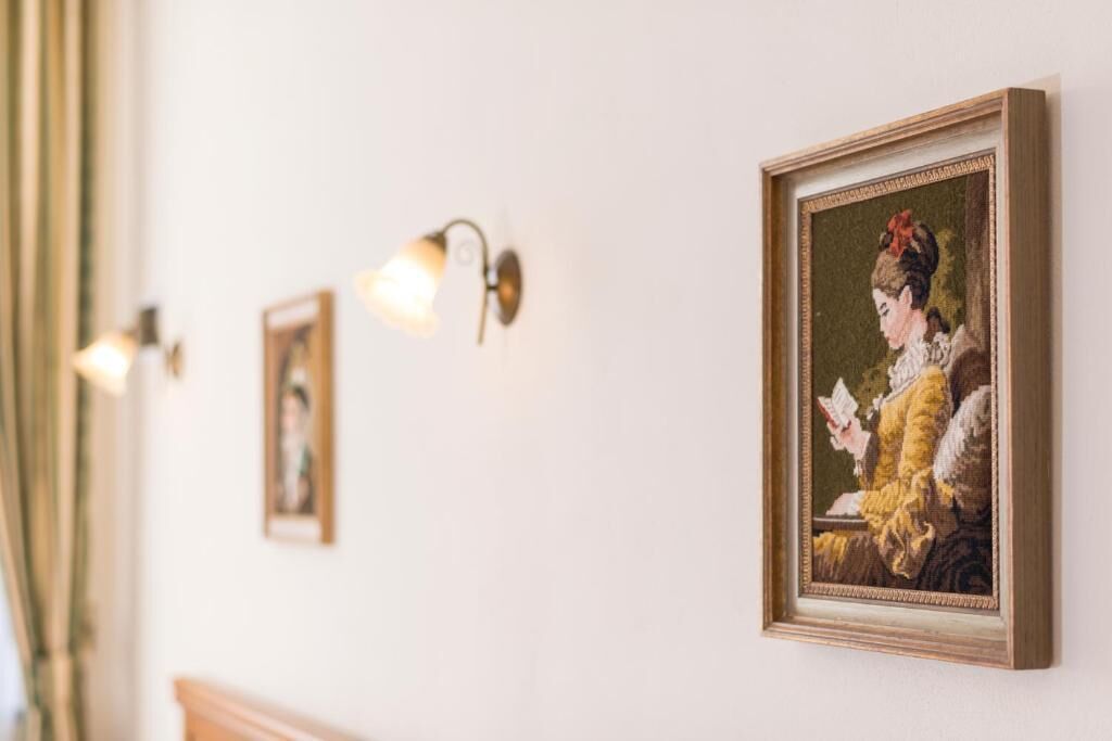 Een gang met kunstwerken in lijsten aan de wanden en wandlampen.