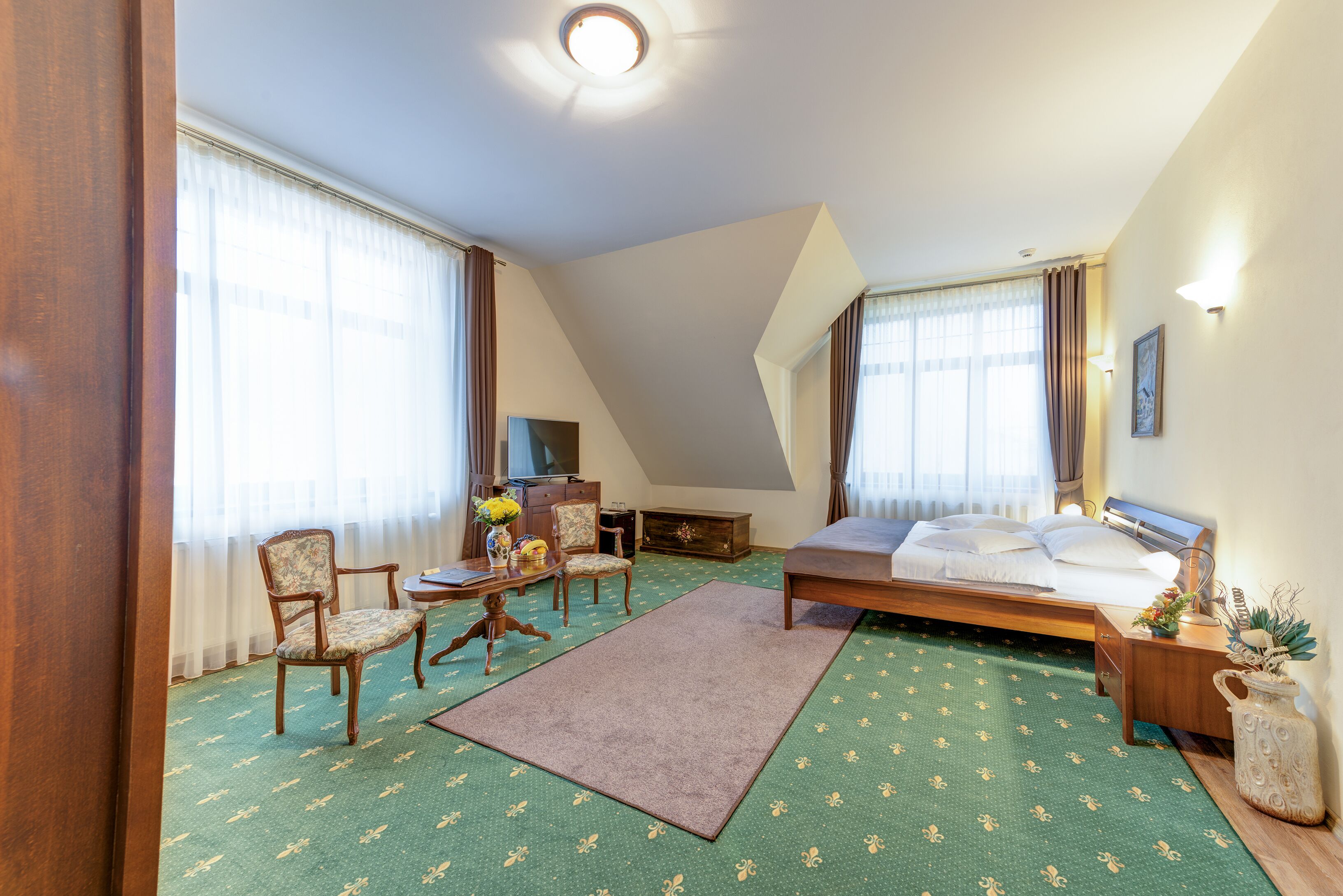 Una habitación de hotel con una cama, dos sillas, un escritorio y un televisor.