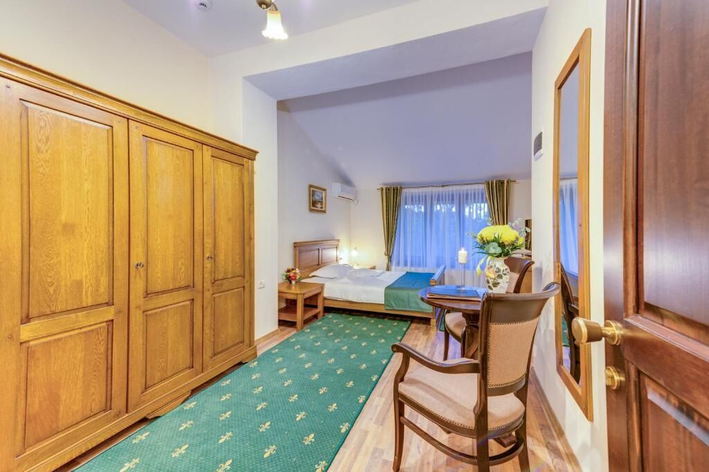A hotel room with a bed, a desk, a chair, and a wardrobe.