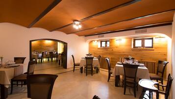 Un restaurante con un interior cálido de madera, varias mesas y sillas.