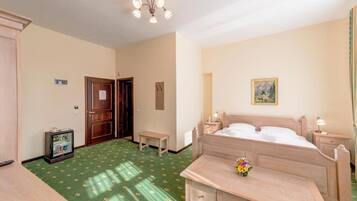 A hotel room with a bed, bedside tables, a small table, a television, and a painting on the wall.