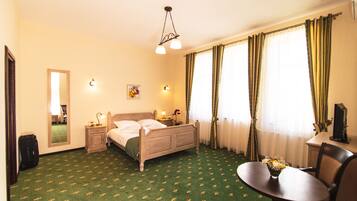 Una habitación de hotel con cama, mesita de noche, lámpara y una pequeña mesa con un jarrón de flores.
