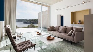 A modern living room with a large glass door leading to a balcony with a scenic view. - Villa Pelagoon  (Skiathos)