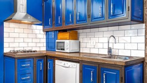 Eine Küche mit blauen Schränken, einer Edelstahl-Dunstabzugshaube, einer Mikrowelle, einem Geschirrspüler und einem Spülbecken.