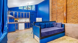 Eine kleine Küche mit blauen Schränken, einer eingebauten Couch und einer Ziegelwand.