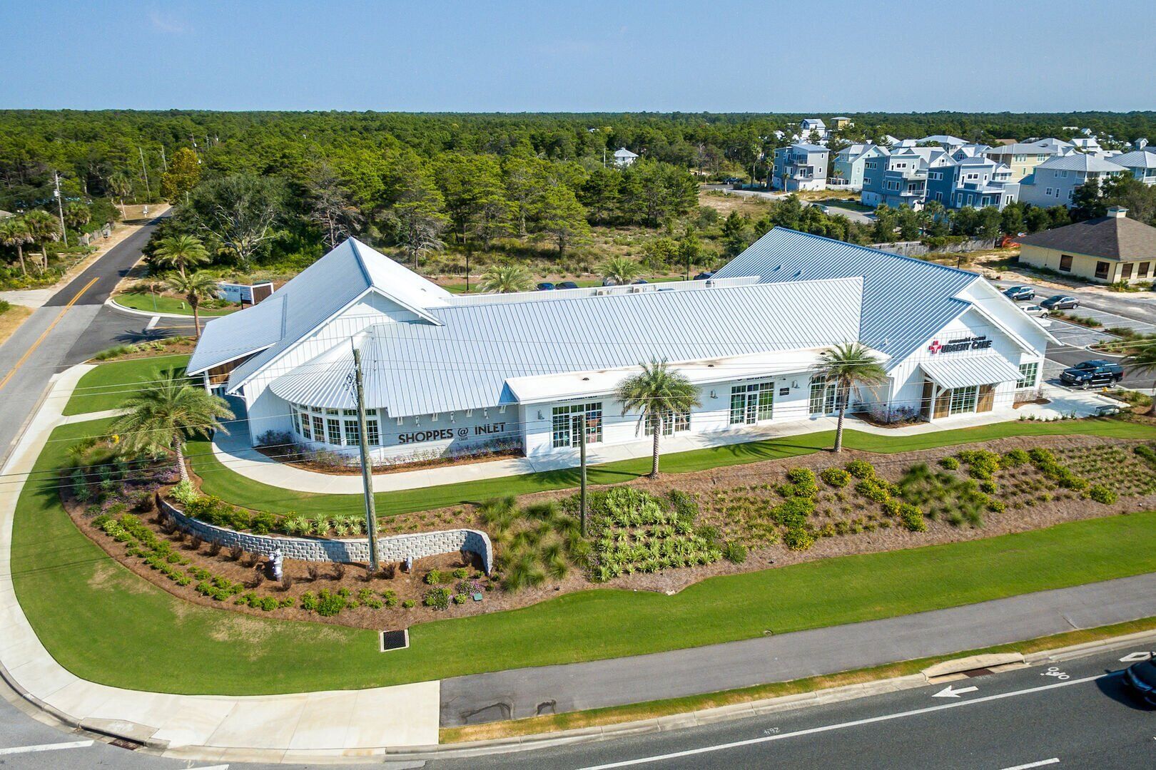A large, modern building with a sloped roof, surrounded by well-maintained lawns and palm trees.