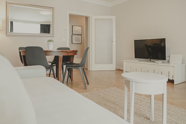 Un salon moderne avec un coin repas, un téléviseur et un canapé blanc.