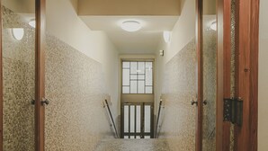 En smal hall med kakel på väggarna, en trädörr på höger sida och ett fönster längst in.