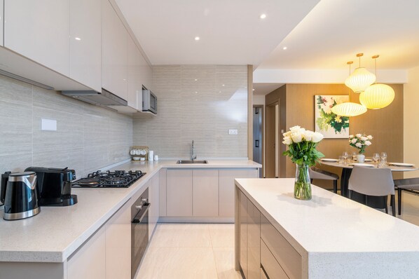Una cocina moderna con una isla central, una zona de comedor con mesa y sillas, y un jarrón con flores sobre la isla.