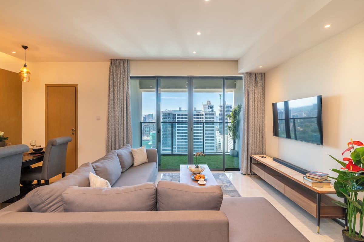 A modern living room with a sofa, a dining table, and a TV.