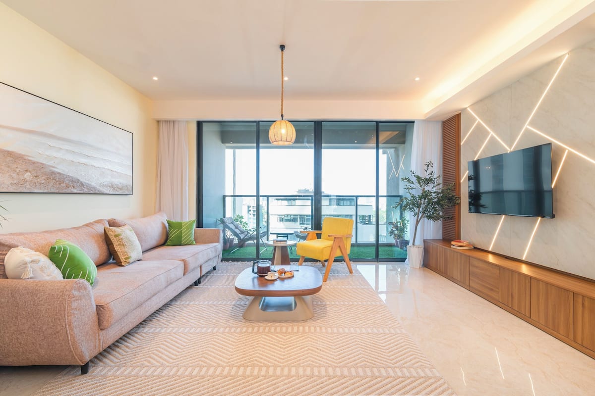 A modern living room with a sofa, coffee table, and a TV mounted on the wall.