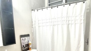 Un baño con inodoro blanco, un mueble negro, un lavabo blanco y una cortina de ducha.