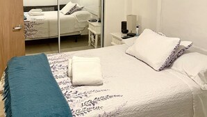 Un dormitorio con cama, mesita de noche, espejo y ventilador de techo.