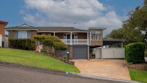 Une maison à deux étages avec un balcon, un garage et une allée.