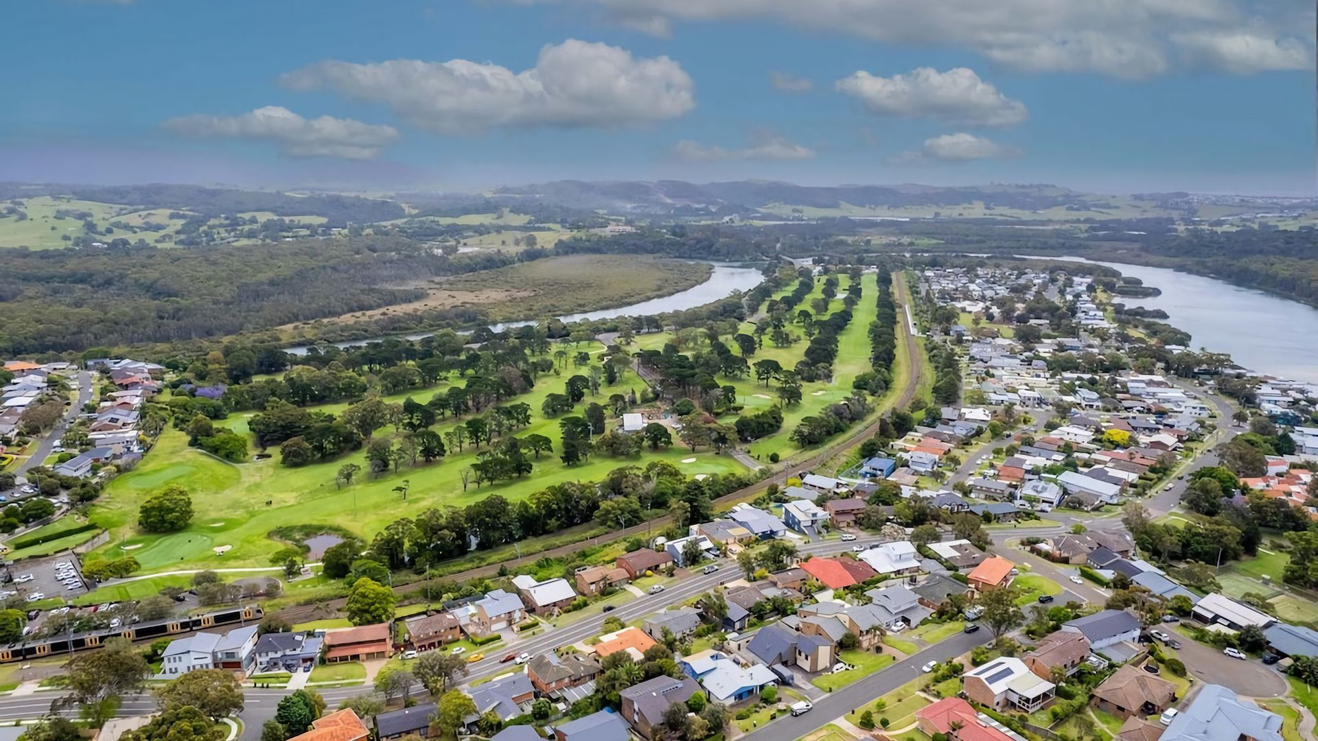 An aerial view of a residential area with houses, roads, and a river.